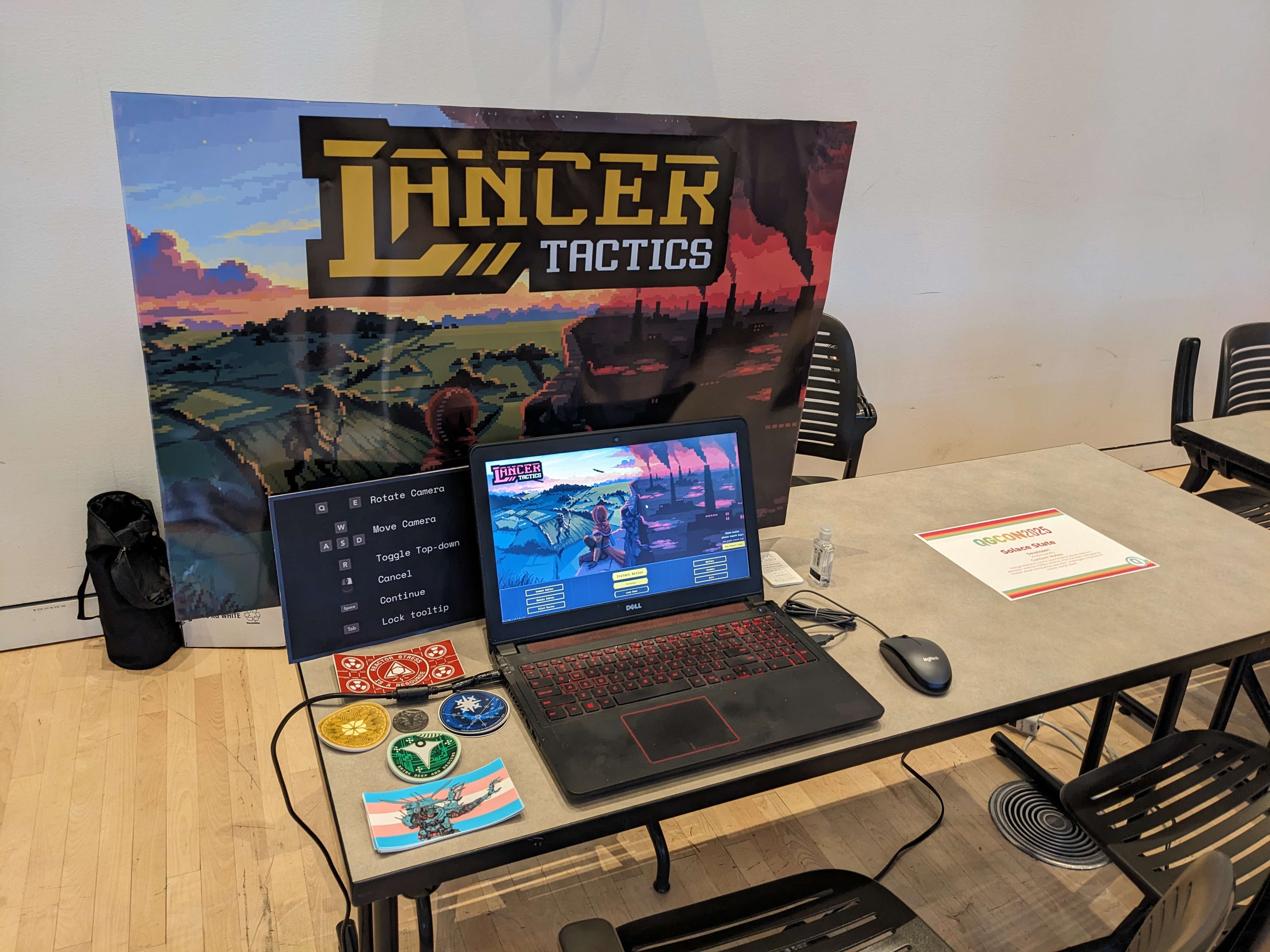 Lancer Tactics modest booth with signage, laptop running the game, and stickers.